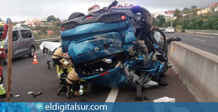 Vista del Nissan Juke azul volcado en la TF-5 tras el accidente, con sus ocupantes siendo liberados por los bomberos