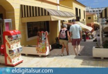 Turistas pasean frente a los comercios de Golf del Sur