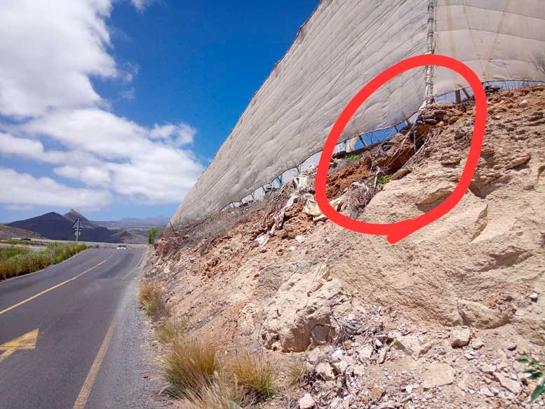 Invernadero elevado junto a la carretera, con rocas sueltas que podrían desprenderse y caer sobre la vía
