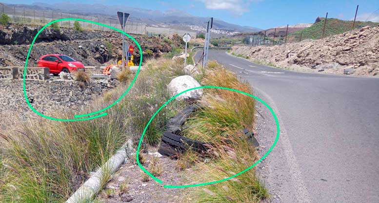 Tramo de la carretera sin defensa lateral, con restos de basura acumulados cerca de la vía
