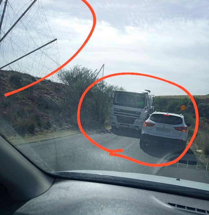 Tramo estrecho de la carretera donde un camión y un coche se cruzan, con circulación dificultada por las condiciones de la vía