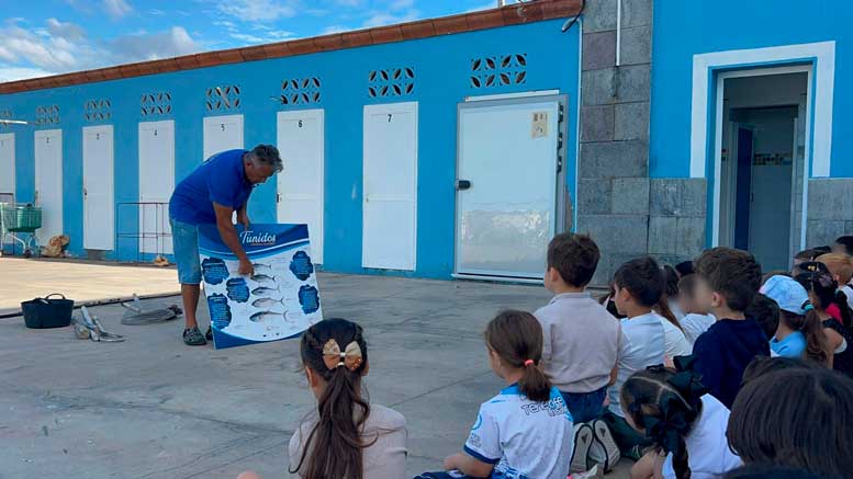 Carlos Braun, en el puerto de Las Galletas, enseñando a los menores los distintos tipos de peces mediante un cartel educativo
